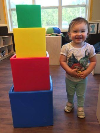 2-year-old_girl_standing_next_to_stacked_blocks_sunbrook_academy_at_woodstock_ga-339x450