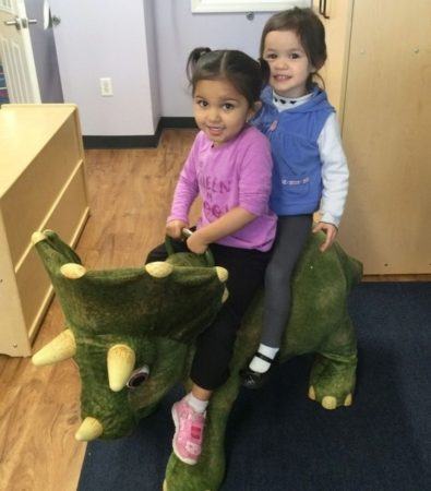 2-year-old_girls_riding_a_dinosaur_cadence_academy_preschool_lincoln_ri-395x450