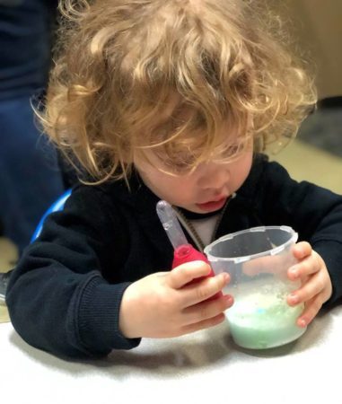 2-year-old_looking_at_goop_in_cup_cadence_academy_preschool_sellwood_portland_or-381x450