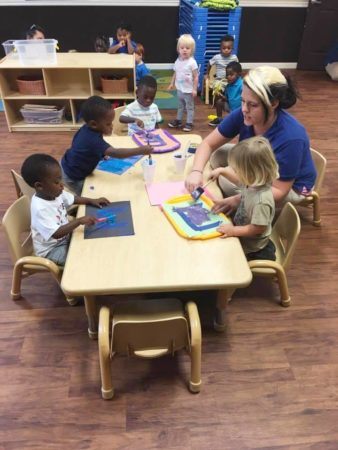 2-year-olds_and_teacher_painting_together_sunbrook_academy_at_luella_mcdonough_ga-338x450