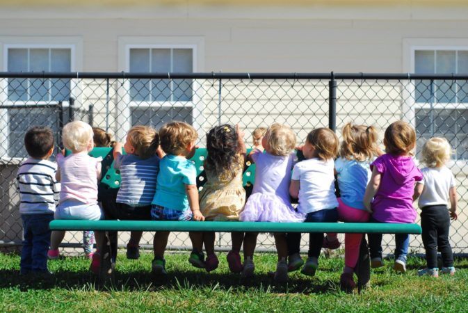 2-year-olds_sitting_on_bench_on_playground-673x450