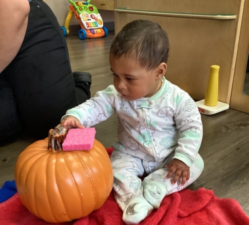 infant with a sponge and a pumpkin at cadence academy preschool and daycare in dupont washington