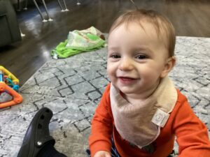 infant smiling at camera while crawling on ground at cadence academy preschool and daycare in dupont washington