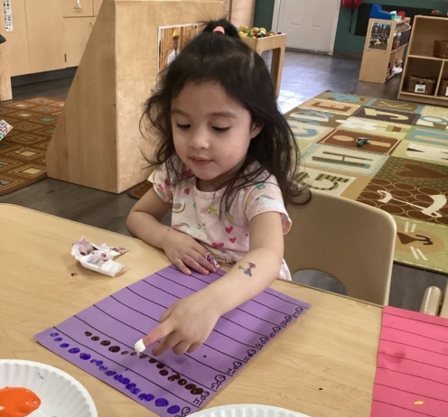 young girl playing with paint to learn numbers at cadence academy preschool and daycare in dupont washington