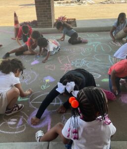 Children playing outside with chalk at cadence academy preschool and daycare branch hollow carrollton texas