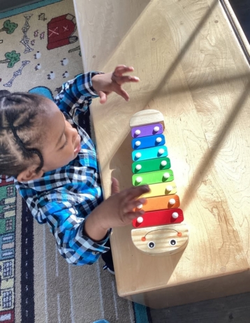 young boy playing with musical instrument at desk at cadence academy preschool and daycare in dupont washington