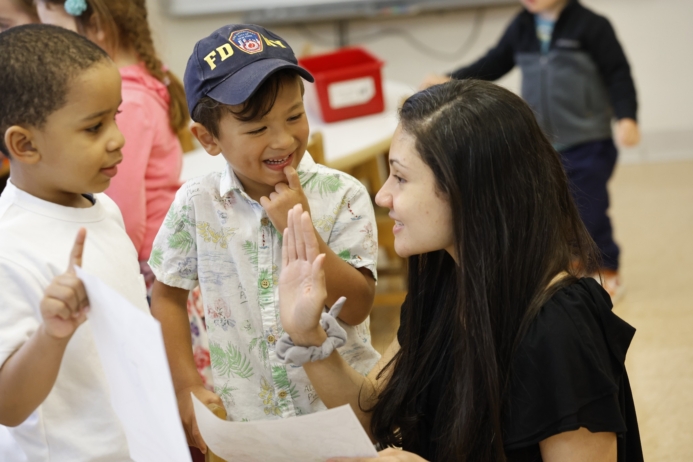 Teacher engaging with a preschool student during a classroom learning activity at Craycroft