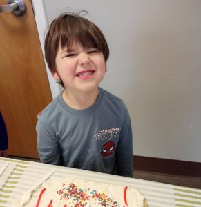 child smiling with baking frosting