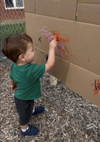 Child painting vertically outside at Crestwood