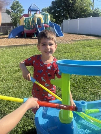 child playing with water outside at crestwood