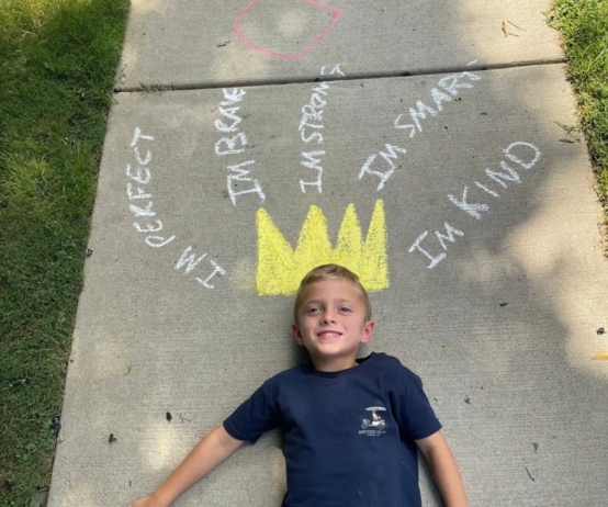 child posing with chalk art crown on sidewalk at preschool and daycare cadence academy preschool 502 spring hill