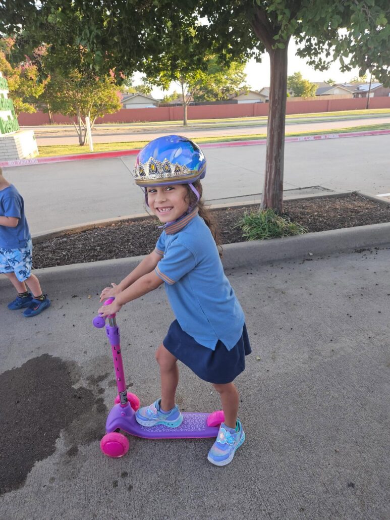 child playing outside on scooter at cadence academy preschool and daycare branch hollow carrollton texas