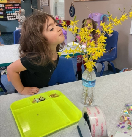 Child smelling flowers inside at Creative Kids Childcare Centers Beekman
