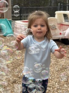 Child playing with bubbles outside on playground at Creative Kids Childcare Centers Beekman