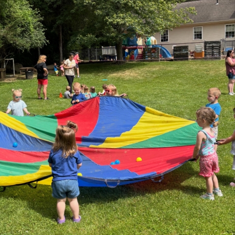 Children playing outside with parachute during summer camp at Creative Kids Childcare Centers Beekman