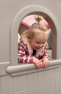 Child peeking head out the window of playhouse at Creative Kids Childcare Centers Beekman
