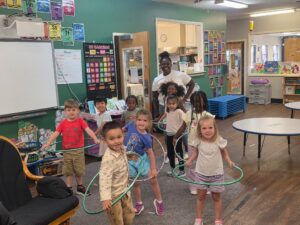 children and teacher hula hooping in classroom at cadence academy preschool and daycare northeast