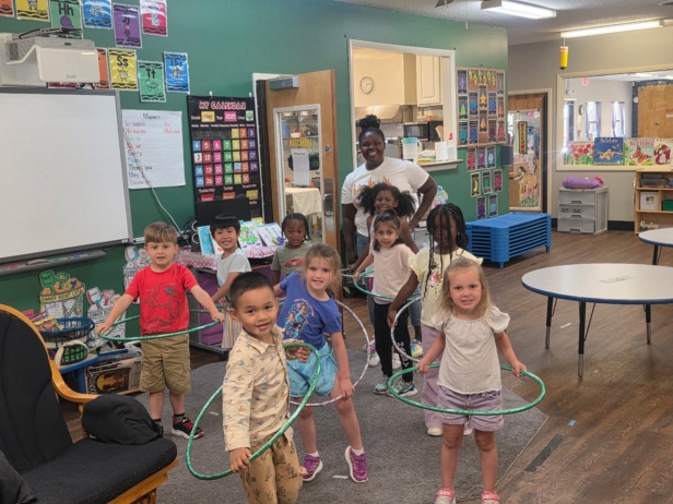 children and teacher hula hooping in classroom at cadence academy preschool and daycare northeast