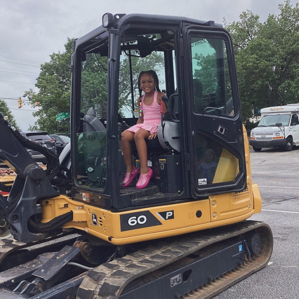 child sitting in excavator during touch-a-truck day at cadence academy preschool and daycare mauldin