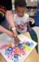 boy child making arts and craft with help of teacher at cadence academy chandler heights