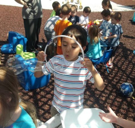 boy_blowing_bubbles_using_large_hoop_cadence_academy_preschool_ashworth_west_des_moines_ia-472x450