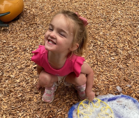 young girl playing outside with bubbles at cadence academy preschool and daycare in dupont washington