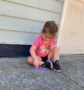 young girl squatting on floor to draw outside with chalk at cadence academy preschool and daycare in dupont washington
