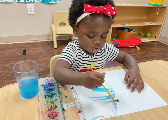 Child doing art painting inside at Cadence Academy Preschool Olive Branch, Mississippi