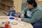 child interacting with teacher with paint at Cadence Academy Preschool and Daycare Yelm Highway in Olympia, Washington
