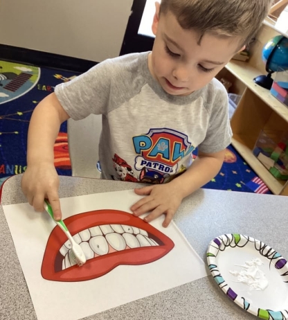 child practicing brushing teeth on paper at preschool and daycare cadence academy preschool nolensville 504
