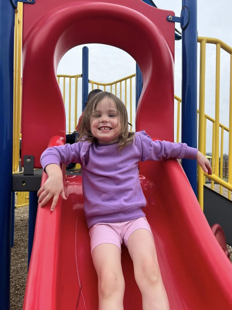 Child sliding down slide at preschool and daycare at cadence academy preschool in the colony texas