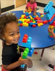 child smiling playing with blocks inside at cadence academy preschool and daycare raintree in charlotte, north carolina