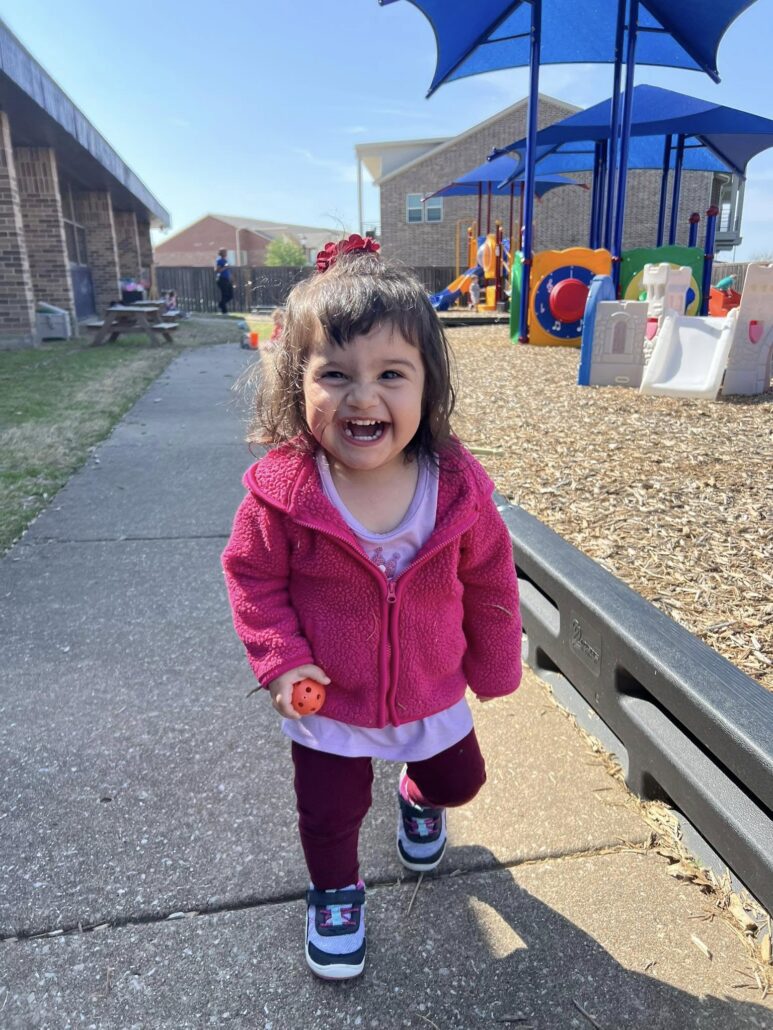 child smiling outside in playground at preschool and daycare at cadence academy preschool in the colony texas