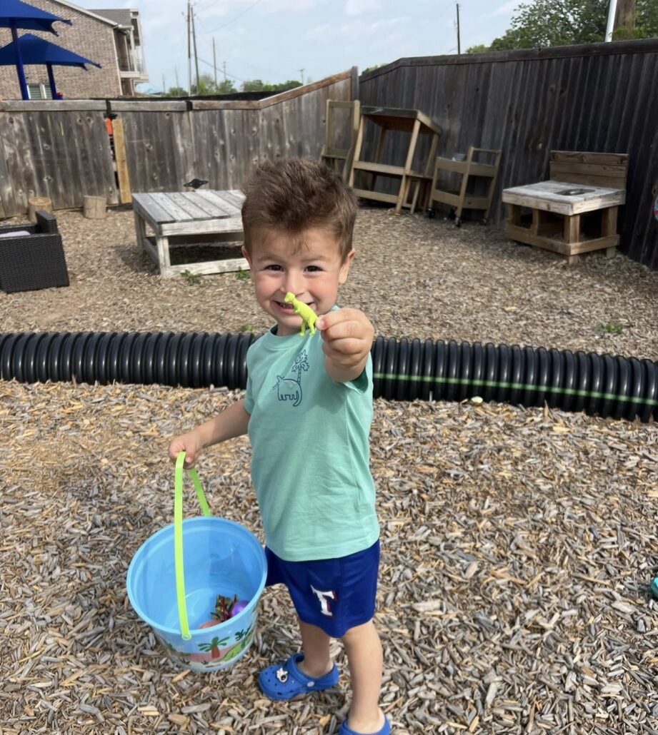 child smiling outside showing toy at preschool and daycare at cadence academy preschool in the colony texas