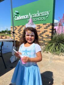 child standing next to cadence sign at preschool and daycare at cadence academy preschool in the colony texas