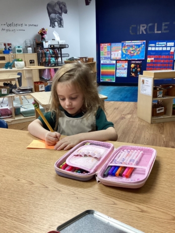 child writing with pencil case at preschool and daycare at cadence academy preschool galleria