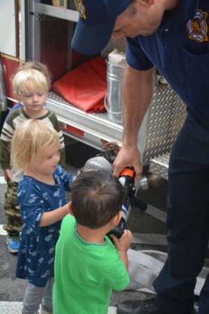 firefighter_showing_preschool_children_hose_at_cadence_academy_preschool_rogers_ar-300x450