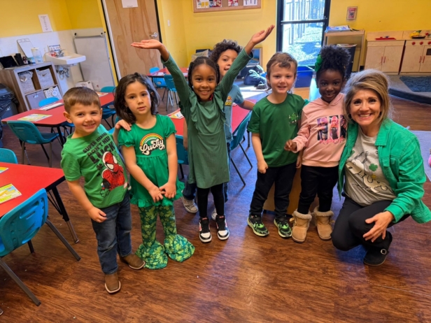 group of children posing smiling with teacher
