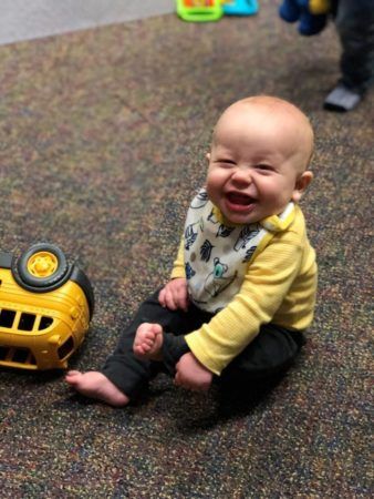 happy_toddler_sitting_on_carpet_cadence_academy_preschool_sellwood_portland_or-338x450