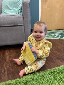 infant smiling with book in classroom at preschool and daycare cadence academy preschool nolensville 504