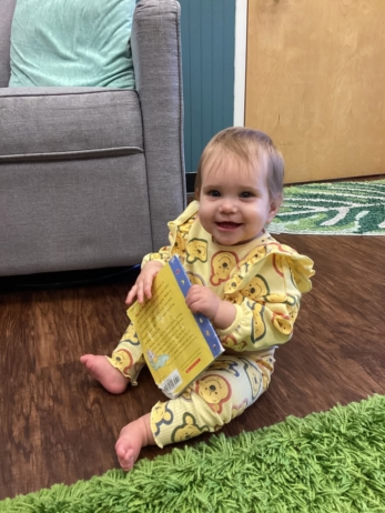 infant smiling with book in classroom at preschool and daycare cadence academy preschool nolensville 504