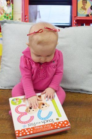 infant_girl_touching_book_at_cadence_academy_preschool_mauldin_sc-300x450