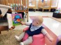 infant_reading_book_in_bumbo_seat_infant_girl_in_pumpkin_halloween_costume_cadence_academy_preschool_mauldin_sc-603x450