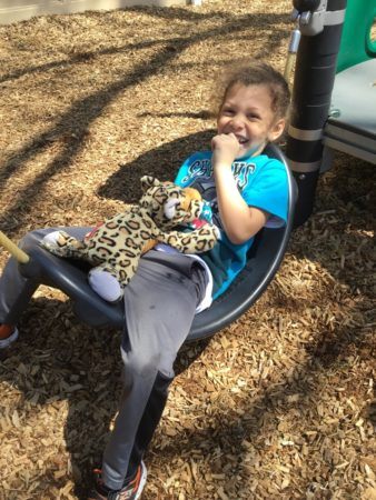 lounging_on_plastic_hammock_on_playground_cadence_academy_preschool_cranston_ri-338x450