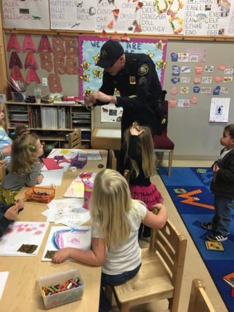 policeman_showing_children_how_handcuffs_work_cadence_academy_preschool_milwaukie_portland_or-338x450