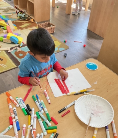 Child painting popsicle sticks with red paint at cadence academy preschool and daycare in dupont washington