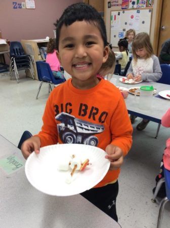 preschool_boy_enjoying_marshmallow_kebob_cadence_academy_preschool_johnston_ia-336x450