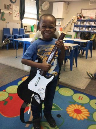 preschool_boy_holding_rock_band_guitar_rogys_learning_place_lake_street_peoria_heights_il-336x450