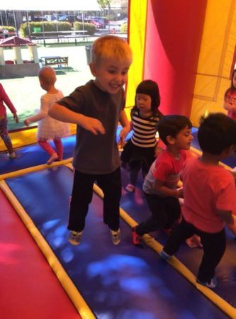 preschool_boy_jumping_in_bounce_house_cadence_academy_preschool_prairie_city_folsom_ca-333x450
