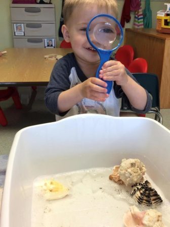 preschool_boy_playing_with_magnifying_glass_at_next_generation_childrens_centers_franklin_ma-336x450